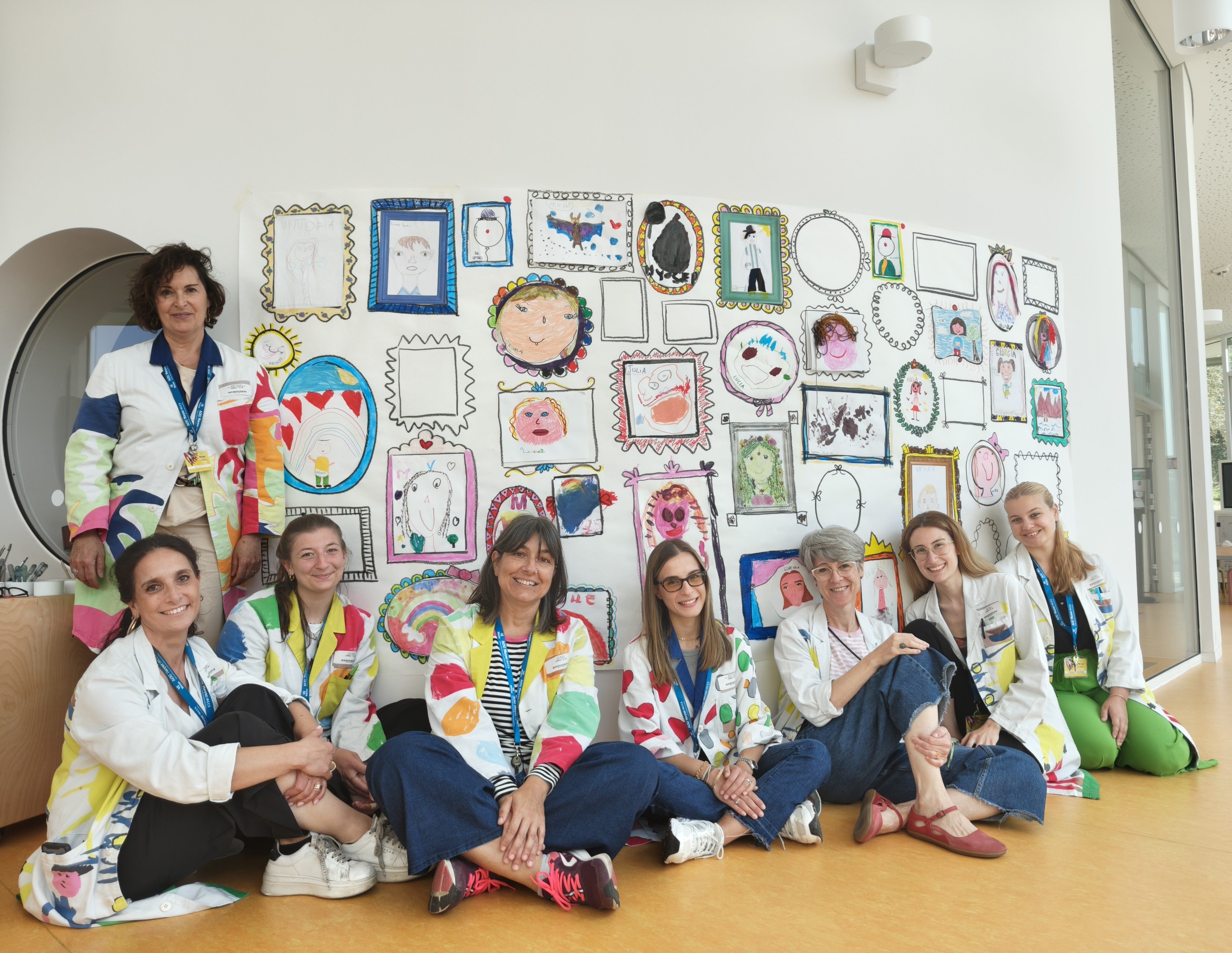 Le docenti davanti alla grande “foto di classe” realizzata con gli autoritratti degli alunni